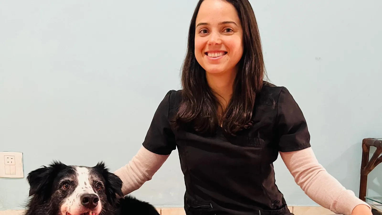 Joyce sentada no tapete de exercícios ao lado de um border collie